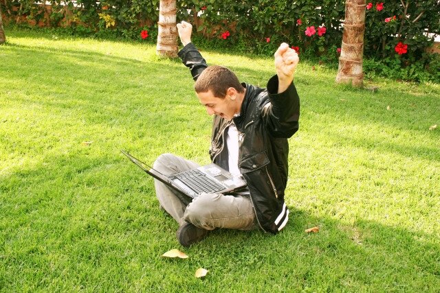 Cheerful winner boy with laptop.